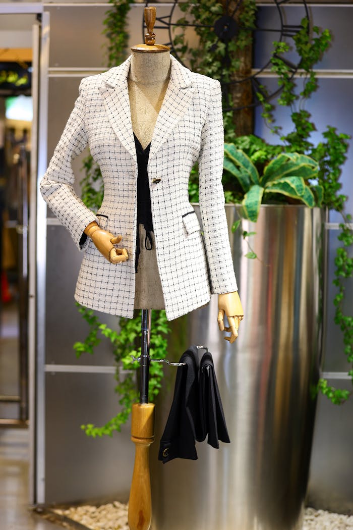 Elegant plaid jacket displayed on a mannequin with plants in a chic clothes store.